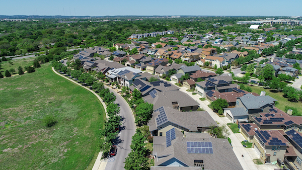 An aerial image of houses with solar panels on the rooftops.