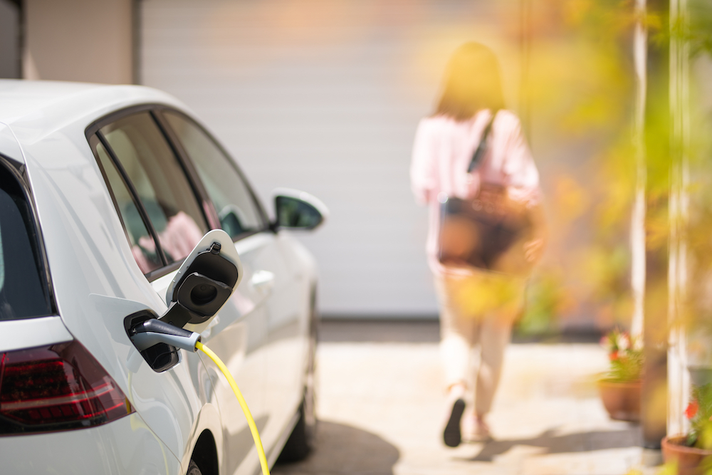 Woman walks away as an electric vehicle is charging.
